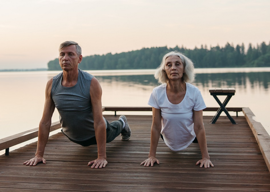 ancianos haciendo yoga al borde de un lago. Son dos ancianos saludables